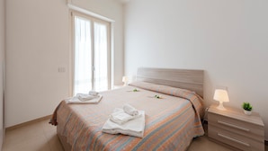 A neatly made bed with a striped bedspread, a bedside lamp, and a small plant on the nightstand. - La Suite 2 Ondina Viareggio 200m from sea (Viareggio)