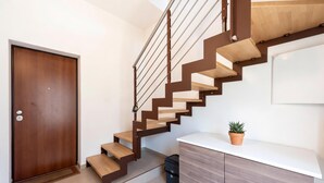 A modern staircase with wooden steps and metal railings, a wooden door, a white countertop with a potted plant, and a cabinet. - La Suite 2 Ondina Viareggio 200m from sea (Viareggio)