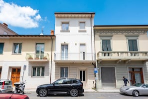 Une vue de rue avec des immeubles, des voitures garées et un ciel dégagé.