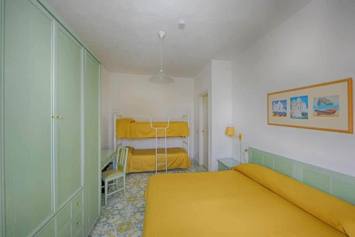 A room with bunk beds, a desk, and a chair.