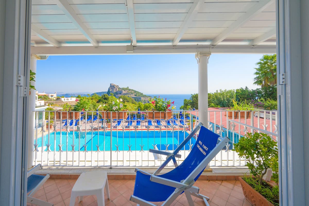 A balcony with a view of a swimming pool, a chair, and a table.