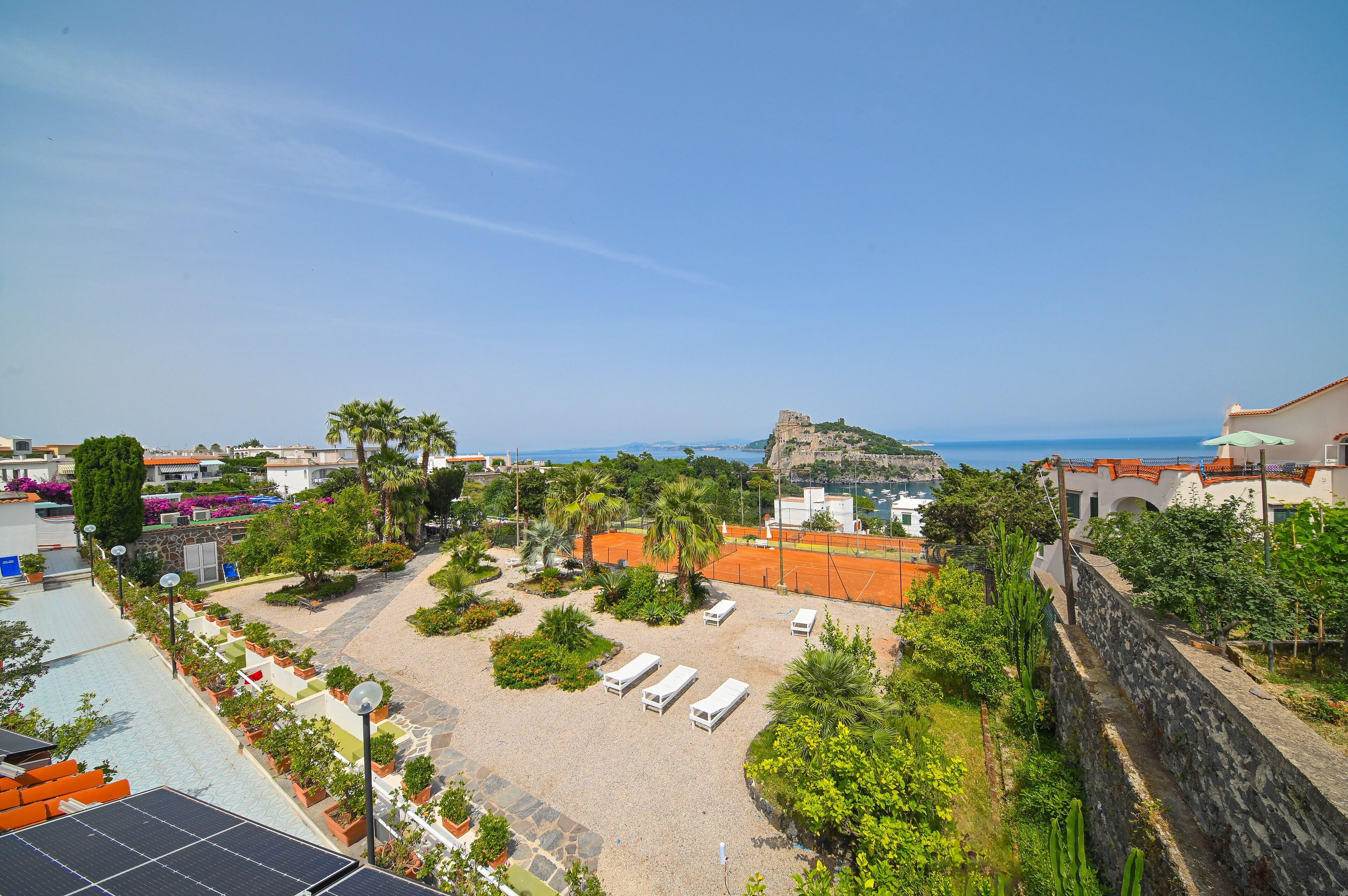 A courtyard with lounge chairs, a stone wall, and a view of a historic fort.