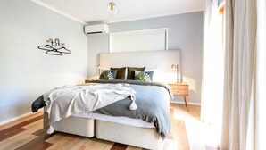 A modern bedroom with a bed, bedside tables, and an air conditioning unit.