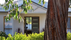 A modern house with a large tree in the foreground, a sliding glass door, and a view of the outdoors.