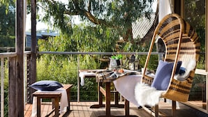 A wooden deck with a wicker chair, a small table, and a bench.