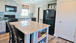 A modern kitchen with granite countertops, stainless steel appliances, and white cabinetry. - PETE'S PARADISE IS MODERN, SPACIOUS FLOOR PLAN! GREAT FENCED IN BACKYARD WITH FIREPIT, PET FRIENDLY! (Port Saint Joe)