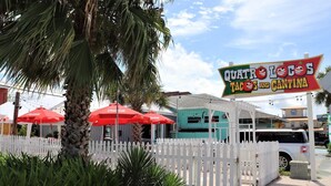 A restaurant named "Quita Tacos and Cantina" with outdoor seating and red umbrellas. - PETE'S PARADISE IS MODERN, SPACIOUS FLOOR PLAN! GREAT FENCED IN BACKYARD WITH FIREPIT, PET FRIENDLY! (Port Saint Joe)