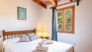 Un lit bien fait, avec une tête de lit en bois, une table de chevet avec une lampe et une fenêtre avec des rideaux.