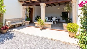 Un espace extérieur aménagé, abrité et doté de bancs en pierre et de plantes en pot.