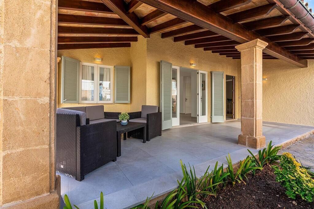 Un'area patio esterna con una zona salotto coperta, un tavolo e una pianta in vaso.