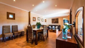 A dining area with a wooden table and wicker chairs, a sofa, and a decorative vase. - Villa Capo, Charming villa located in a peaceful rural area (Sa Pobla)