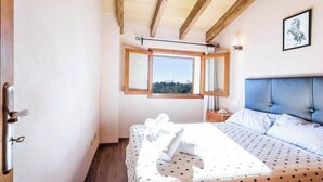 A bedroom with a bed, a window with a view, a headboard, and a wall-mounted artwork. - Villa Capo, Charming villa located in a peaceful rural area (Sa Pobla)