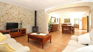 A living room with a stone wall, a television, a fireplace, and a dining area with wooden furniture.