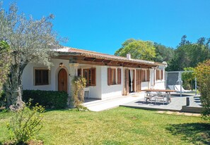 A white building with a tiled roof, wooden shutters, and a patio area with a table and chairs. - Villa Alegre, Relax just outside Pollensa recently renovated (Pollença)