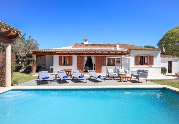A poolside area with lounge chairs and a building with a tiled roof. - Villa Alegre, Relax just outside Pollensa recently renovated (Pollença)
