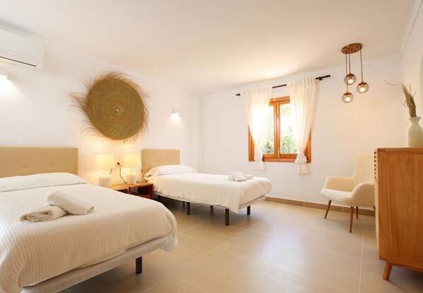 Une chambre d’hôtel avec deux lits, une commode en bois, une chaise et une fenêtre avec des rideaux.