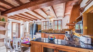 A spacious kitchen with wooden beams, a large island, and modern appliances. - Finca Rafalet, Charming villa close to Pollensa (Pollença)