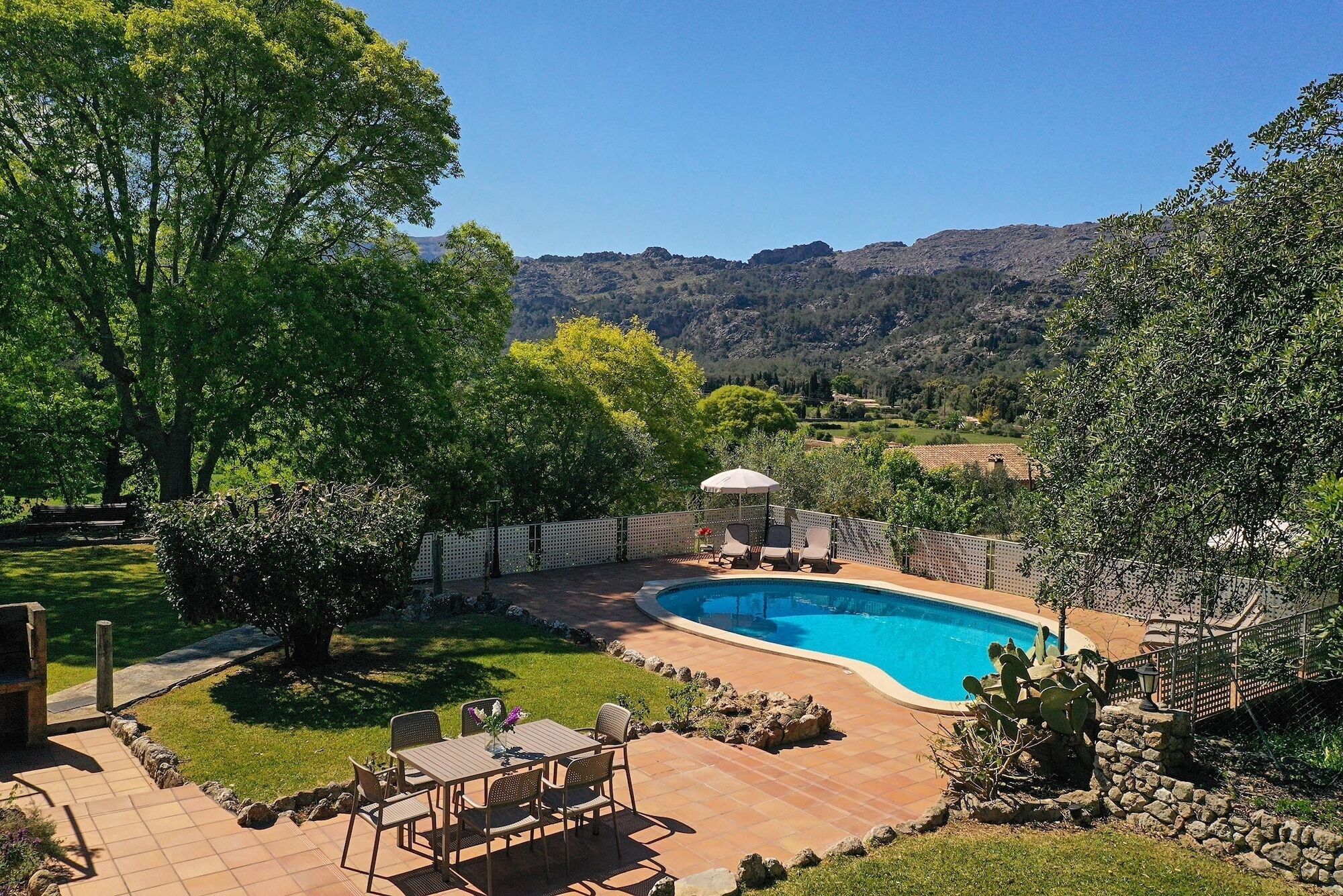 Un patio trasero con piscina, muebles de jardín y vistas del paisaje circundante.