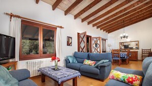 A living room with a sofa, a coffee table, a TV, and a dining area with a table and chairs. - Villa Porqueres, Charming house with pool near Pollensa (Pollença)