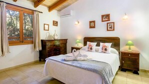 A bedroom with a wooden ceiling, a bed with white bedding, two bedside tables with lamps, and framed pictures on the wall. - Villa Geroni, Charming 3 bedroomn villa with pool (Pollença)
