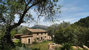 A rustic stone house with a tiled roof, surrounded by lush greenery and a mountain in the background. - Ca'n Pascol, Villa over 250 years old in a breathtaking setting (Pollença)