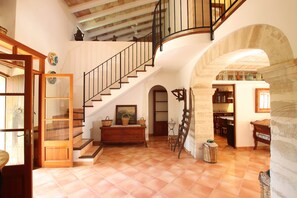 Un interior espaiós amb una escala de fusta, una zona de menjador i una cuina visible a través d'una volta.