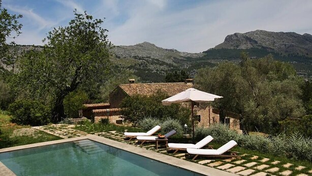 A pool area with lounge chairs and umbrellas, surrounded by greenery and a mountain backdrop. - Ca'n Pascol, Villa over 250 years old in a breathtaking setting (Pollença)