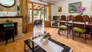 A dining area with a wooden table and chairs, a fireplace, and a view of the outdoors. - Villa Sol Roma, 3 bedrooms villa  with pool near Pollensa (Pollença)