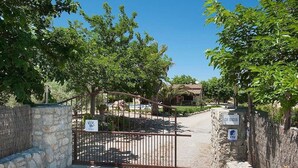 A gated entrance to a property with a stone wall on one side and a metal gate. - Villa Burgues, Idyllic location affording beautiful views. Alcudia (Alcúdia)