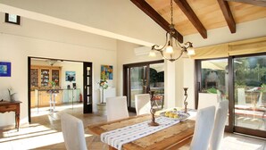 A spacious dining area with a wooden table, white chairs, and a chandelier. - Villa LLop, Magnificent modern villa with sauna (Pollença)