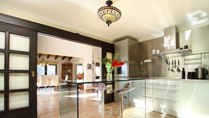 A modern kitchen with stainless steel appliances, a glass dining table, and a decorative chandelier. - Villa LLop, Magnificent modern villa with sauna (Pollença)