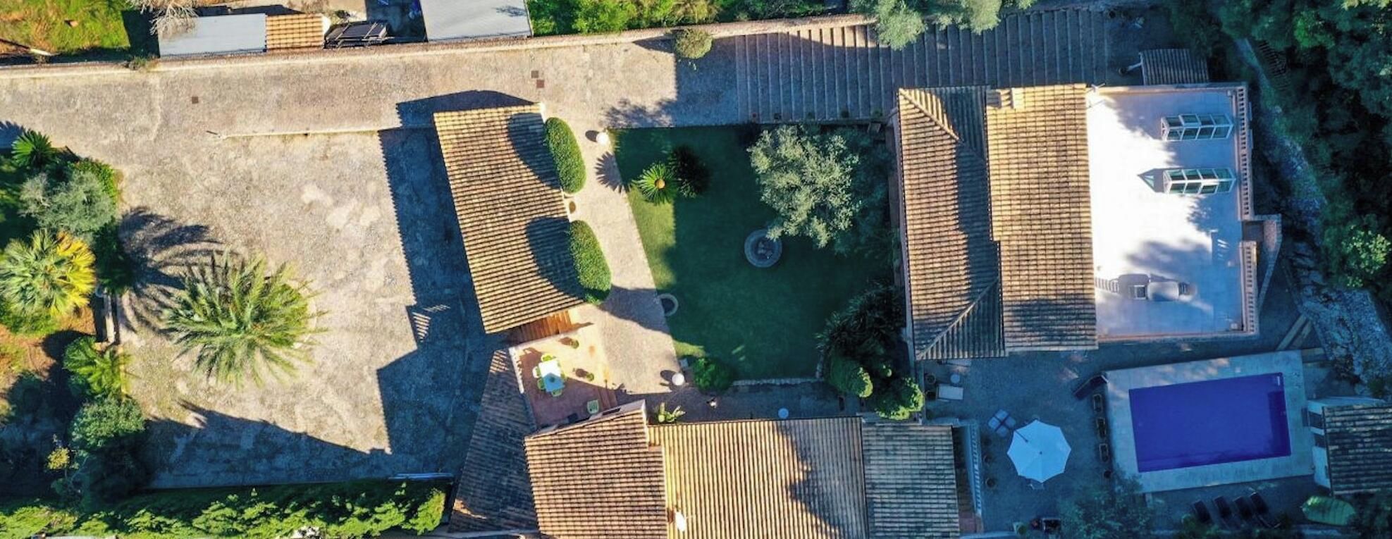 Luchtbeeld van een pand met een zwembad, terras en een tuin met palmbomen.
