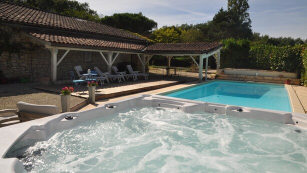 Uma banheira de hidromassagem com teto em azulejos, uma piscina e cadeiras de lounge.