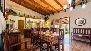 Un coin repas avec des meubles en bois, une table dressée pour quatre personnes et une cuisine en arrière-plan.