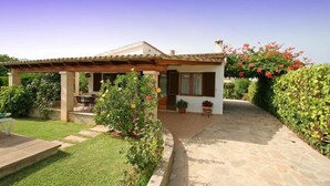 Une petite maison avec un patio, un jardin et un chemin en pierre.