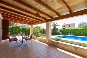 An outdoor patio with a pool, covered seating, and a view of the surrounding greenery and buildings. - Villa Jaume, Cozy house in a quiet rural area in Pollensa (Pollença)