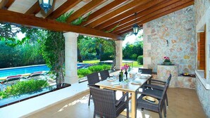 Eine Außenpatio mit Steinmauer, Pool und Essbereich.