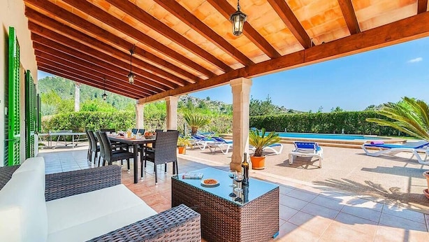 Un espacio al aire libre cubierto con piscina, mobiliario de mimbre y una mesa con sillas.