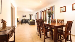 A dining area with a wooden table and chairs, a sofa, and a vase with flowers. - Villa  Can Mares, Elegant and modern house designed with comfort and style (Pollença)