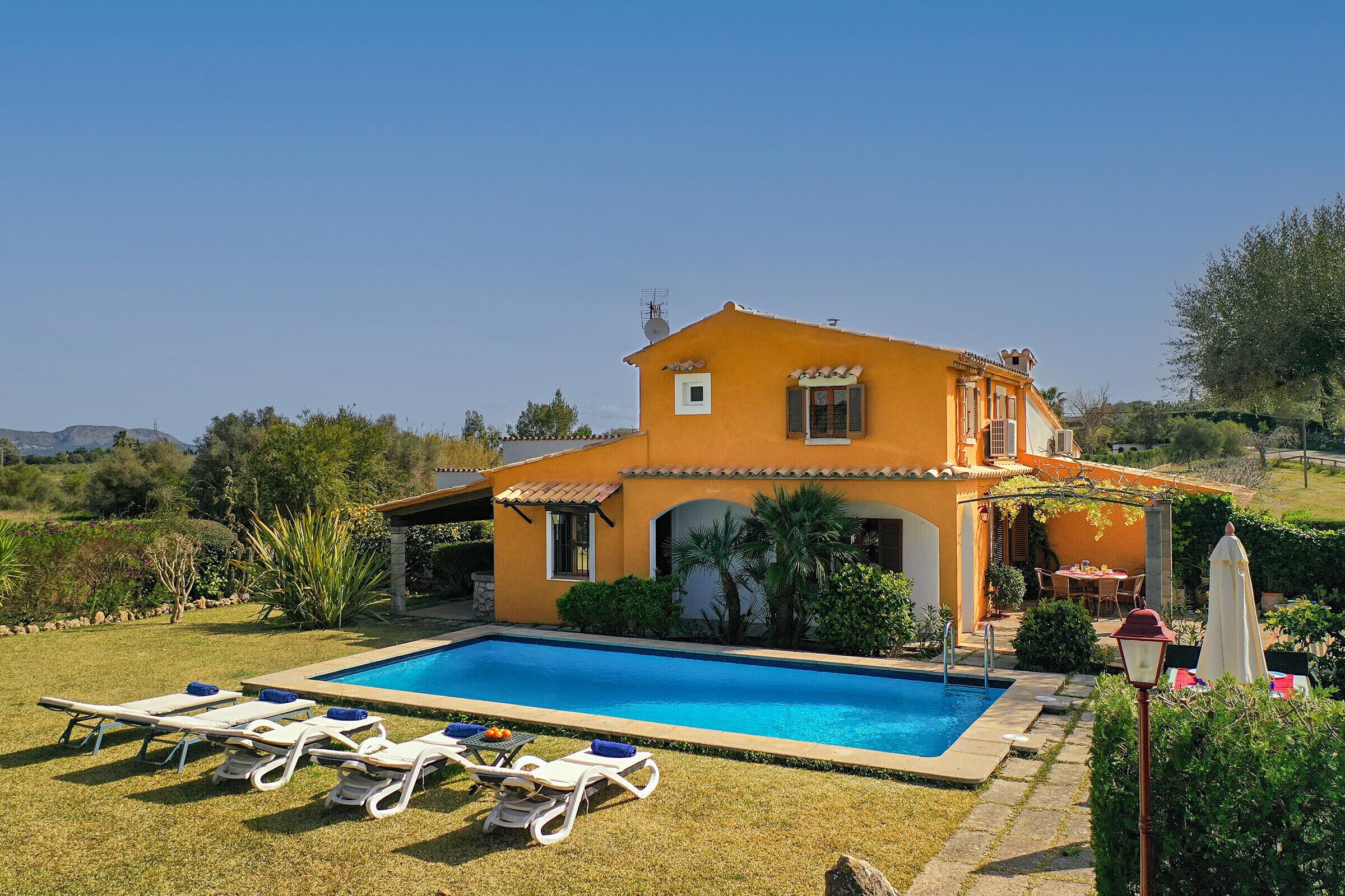 Una casa de dos pisos con piscina, rodeada por un césped y jardín cuidados.