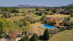 Una villa con piscina, rodeada de exuberante vegetación y montañas al fondo.
