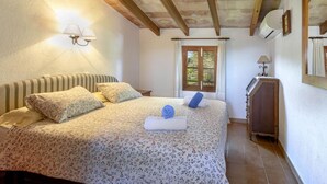 Un dormitorio con cama, mesita de noche, cómoda y ventana con cortinas.