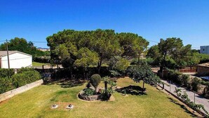 A residential area with a well-maintained lawn, a small garden with various plants, and a few trees. - Villa Animeta, Hermosa villa cerca de Port Pollensa (Pollença)