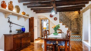 A rustic dining area with a wooden table and chairs, a hanging light fixture, and a staircase leading to an upper level. - Villa Piedra, Surrounded by nature, but close to Port Pollensa (Pollença)