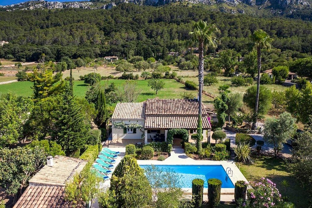 Una villa con piscina, rodeada de exuberante vegetación y montañas.