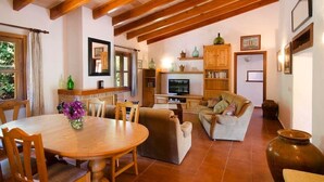 A cozy living room with a wooden dining table, chairs, a sofa, and a television. - Villa Varella, Pretty villa close to Pollensa (Pollença)