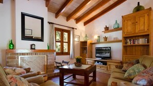 A cozy living room with a fireplace, wooden furniture, and a television. - Villa Varella, Pretty villa close to Pollensa (Pollença)