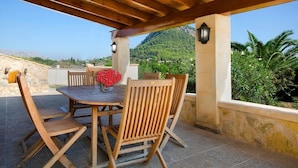 An outdoor patio with a wooden table and chairs, a vase of red flowers, and a view of a mountainous landscape. - Villa Varella, Pretty villa close to Pollensa (Pollença)