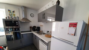 Una cocina moderna con electrodomésticos de acero inoxidable, un refrigerador blanco y una encimera de madera.