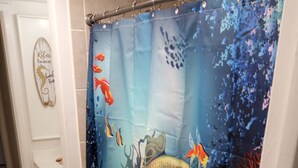 A bathroom with a shower curtain featuring an underwater scene with fish and coral. - Mermaids Retreat Mins to Beach Family Condo (Destin)